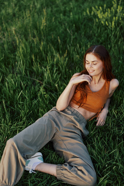 Nuori onnellinen nainen makaa rento nurmikolla puistossa, elämäntapa onnellinen henkilö ilman masennusta. Laadukas kuva - Valokuva, kuva