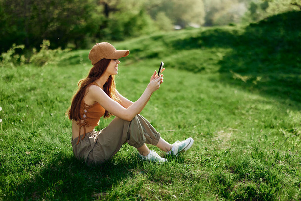 Mujer independiente trabajando en su teléfono contra un paisaje verde de verano, el estilo de vida de un blogger. Foto de alta calidad - Foto, imagen