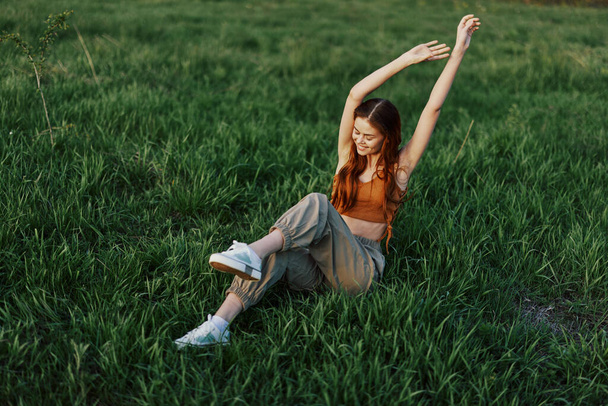 Žena leží na zelené trávě v parku s nohama nad hlavou a baví se na trávníku, shora. Koncept relaxace v přírodě a péče o životní prostředí. Kvalitní fotografie - Fotografie, Obrázek
