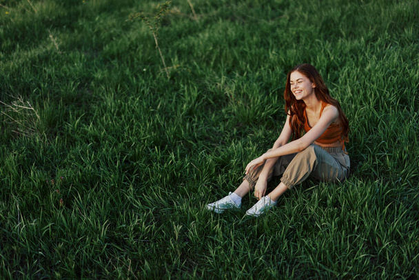 Woman sitting on green grass in nature in a park, view from above. High quality photo - Photo, Image