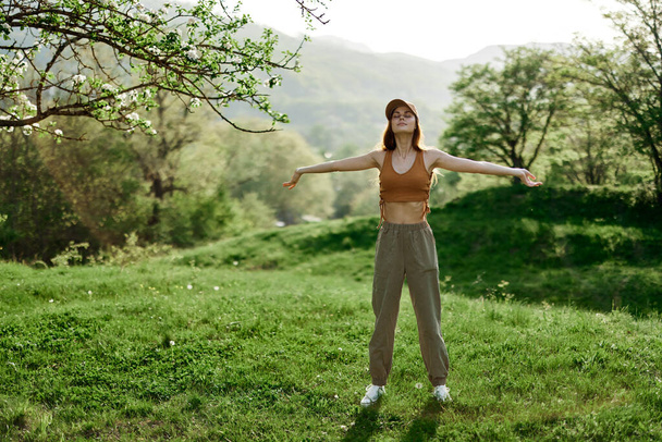 Μια γυναίκα περπατά στο πάρκο και κάνει γιόγκα και απολαμβάνει τον καθαρό καλοκαιρινό αέρα. Τρόπος ζωής και το μυαλό και την υγεία του σώματος. Υψηλής ποιότητας φωτογραφία - Φωτογραφία, εικόνα