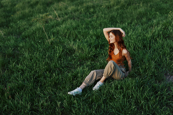 Жінка сидить на зеленій траві в природі в парку, вид зверху. Високоякісна фотографія - Фото, зображення