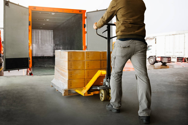 作業者パレットの包装箱を貨物コンテナトラックにアンロードします。ドックを積み込め。倉庫だ。配達だ。出荷品。サプライチェーン。倉庫物流貨物輸送. - 写真・画像