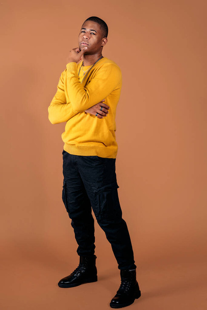 Stock photo of young man wearing casual clothes posing in studio shot against brown background. - Foto, Bild