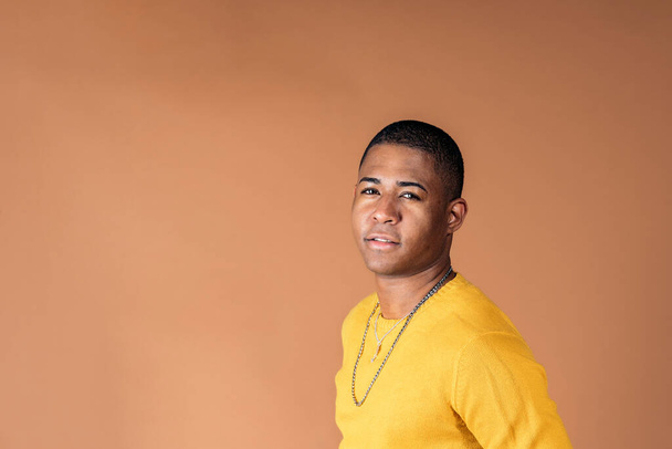 Young man wearing casual clothes smiling in studio shot against brown background. - Foto, imagen