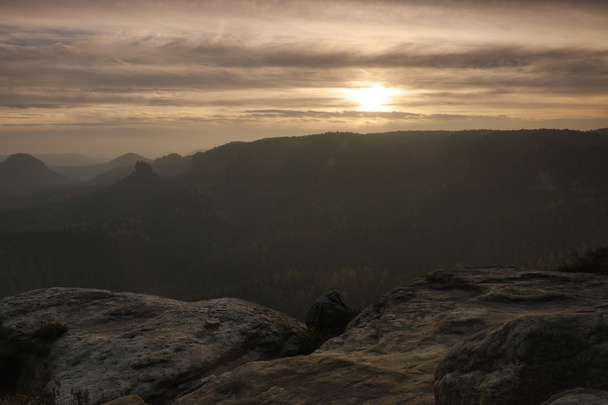 Zonsondergang in een prachtige rotsachtige park Boheemse-Saksen Zwitserland. Zandsteen pieken en heuvels steeg van mistige achtergrond, de mist is oranje als gevolg van zonnestralen. - Foto, afbeelding