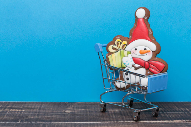 in a trolley from the supermarket is gingerbread in the shape of a Christmas snowman, the concept of shopping - Photo, Image