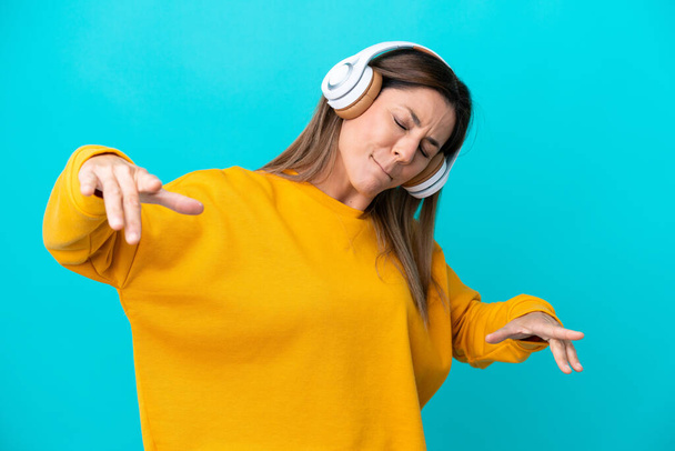 Middle age caucasian woman isolated on blue background listening music and dancing - Foto, immagini