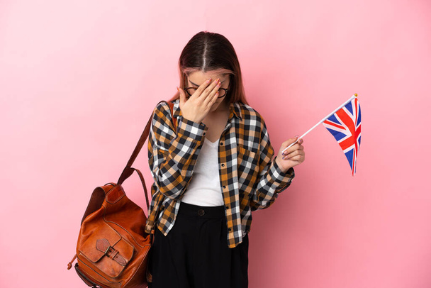Young hispanic woman holding an United Kingdom flag isolated on pink background with tired and sick expression - Fotó, kép