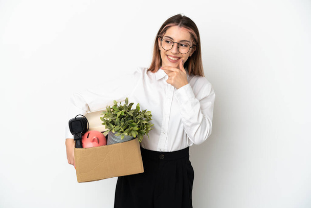 Young caucasian woman moving in new home among boxes isolated on white background looking to the side and smiling - Valokuva, kuva