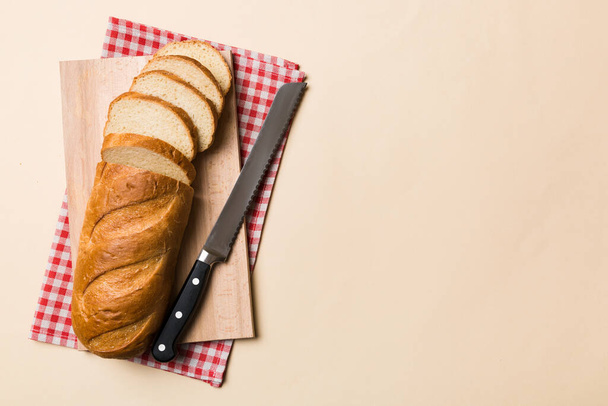 Свежеиспеченный хлеб, порезанный ножом на деревянной доске. вид сверху Нарезанный хлеб и нож. - Фото, изображение