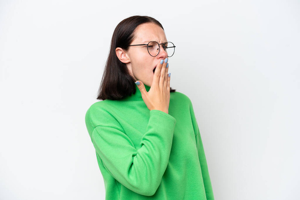 Nuori valkoihoinen nainen eristetty valkoisella taustalla haukottelu ja kattaa leveä suu käsin - Valokuva, kuva