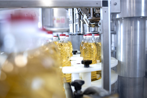 Zonnebloemolie in flessen die in een levensmiddelenfabriek worden geproduceerd. - Foto, afbeelding