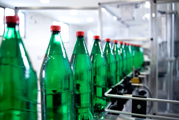 Промышленное производство питьевой воды и бутылок, перемещаемых на транспортерной ленте. - Фото, изображение