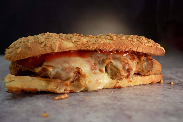 A closeup of a tasty meatball sandwich with melted parmesan and marinara sauce - 写真・画像