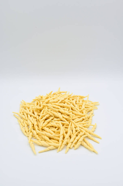 A vertical shot of raw trofie pasta on a white background - 写真・画像