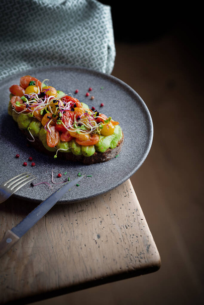 A vertical closeup of grilled bread with avocado puree and vegetables. Delicious meal. - Foto, afbeelding