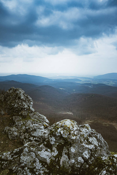A closeup shot of rocks on a mountain under the cloudy sky - Zdjęcie, obraz