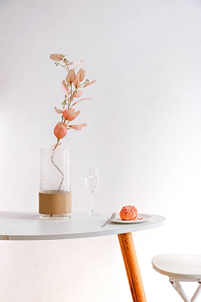 Вертикальний знімок шматочка кексу і квітів на столі на білому тлі
 - Фото, зображення