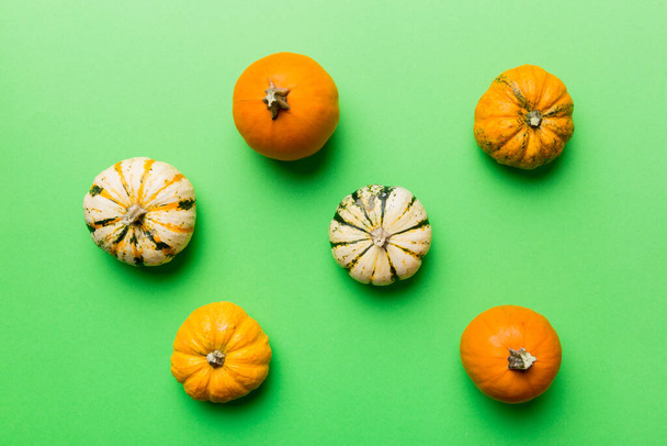 Herfst samenstelling van kleine oranje pompoenen op gekleurde tafel achtergrond. Herfst, Halloween en Thanksgiving concept. Herfst platte lay fotografie. Bovenaanzicht vith kopieerruimte. - Foto, afbeelding