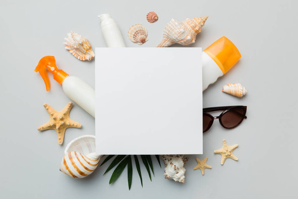 Summer time concept with blank greeting card and blank white paper on colored background. Seashells from ocean shore in the shape of frame separated with space for text top view. - Foto, immagini