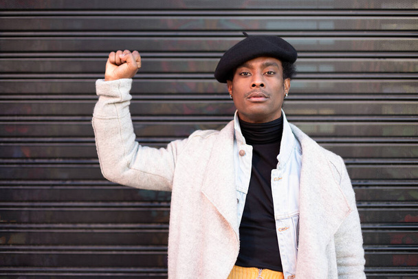 Αφροαμερικάνος νεαρός άνδρας με σηκωμένη γροθιά σε ένδειξη διαμαρτυρίας κατά της βίας με μαύρους. Οι μαύρες ζωές έχουν σημασία. Σταματήστε τον ρατσισμό. - Φωτογραφία, εικόνα
