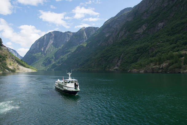 A white ship sailing on the water surrounded by breathtaking mountain view - Valokuva, kuva