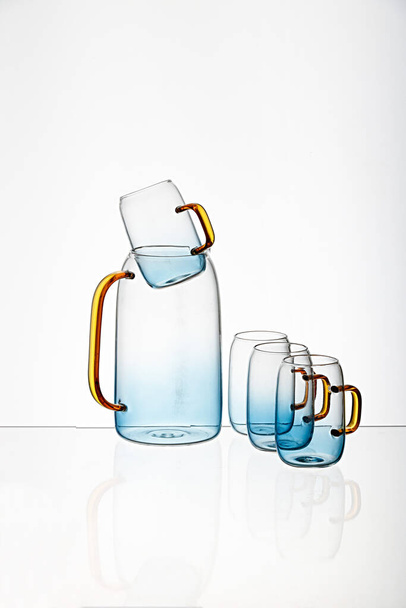 The vertical shot of a glass blue transparent  cups and juice pot with a white background - Photo, image