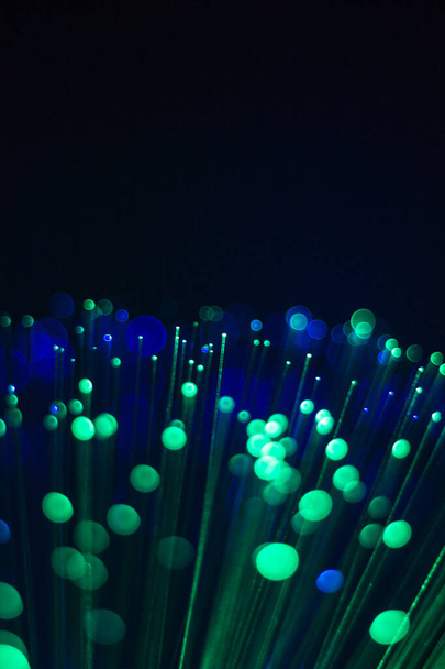 An abstract background of a Bundle of optical fibers with green light on a Black background. - 写真・画像