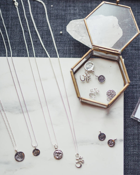 A vertical shot of necklaces with different pendants on a white and blue surface - Foto, Imagen