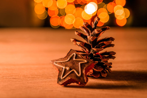 A closeup shot of a pine cone with a Christmas decoration with bokeh lights in the background - Zdjęcie, obraz