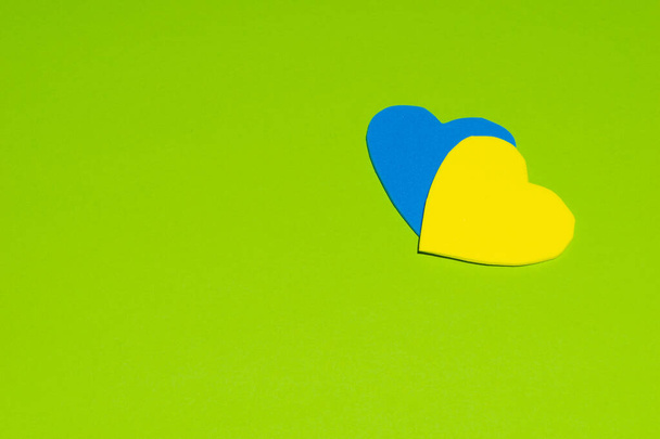 A top view of a blue and yellow heart cutouts with a green background - Fotó, kép