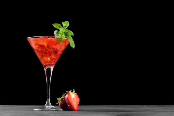 Cocktail froid d'été aux fraises mojito, margarita, daiquiri dans un verre de martini. Boisson fraise fraîche avec glace et feuilles de menthe sur fond noir foncé. Fraise glacée limonade espace de copie - Photo, image