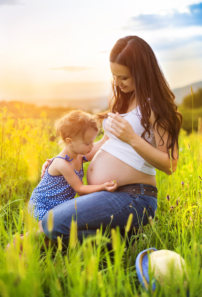 Girl touching her mother's pregnant belly - Valokuva, kuva