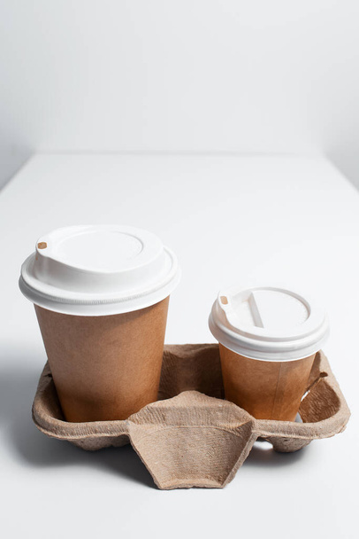 Soporte de cartón con tazas de café para llevar sobre mesa blanca. - Foto, Imagen