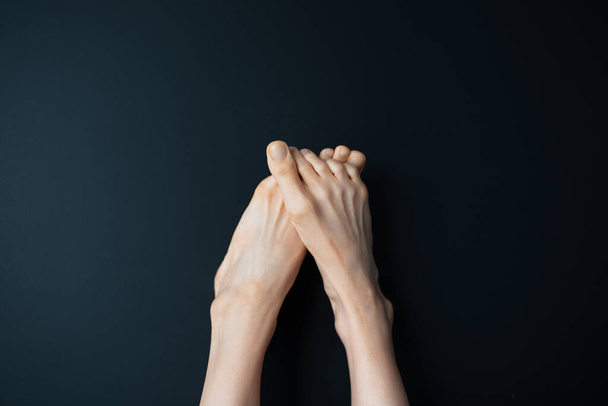 Nahaufnahme weiblicher Füße auf schwarzem Hintergrund. - Foto, Bild