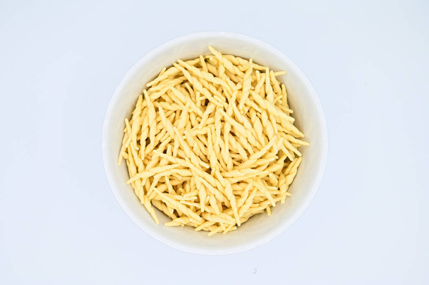A top view of raw trofie pasta on a white background - Zdjęcie, obraz