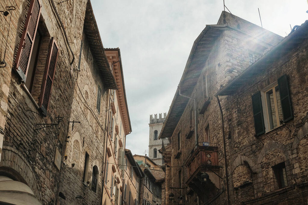 The old brick buildings with windows against a cloudy sky in Assisi, Italy - Foto, afbeelding