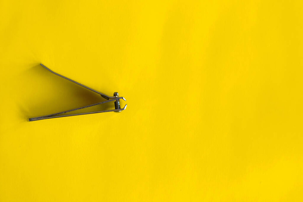 A closeup of a nail clipper isolated on bright yellow background. - Foto, afbeelding