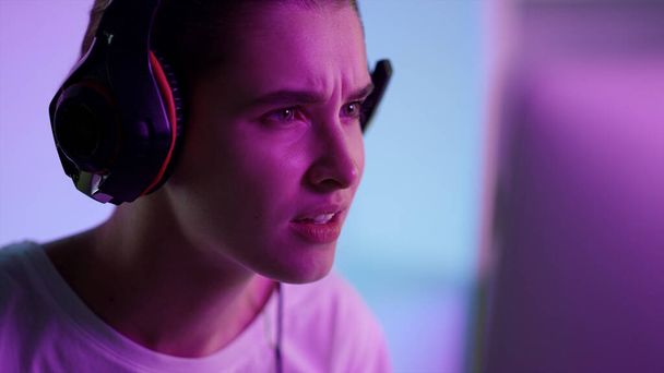 Esport játékos néz képernyő neon fények közelkép. Stressz lány a kibertérben játszik számítógépes játék elvesztése virtuális csata headset. Érzelmi játékos pihen a hétvégén. Millenniumi hobbi koncepció. - Fotó, kép