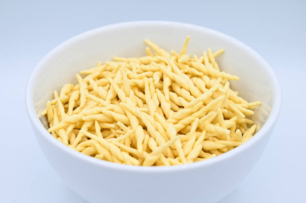 A closeup of raw trofie pasta on a white background - Фото, зображення