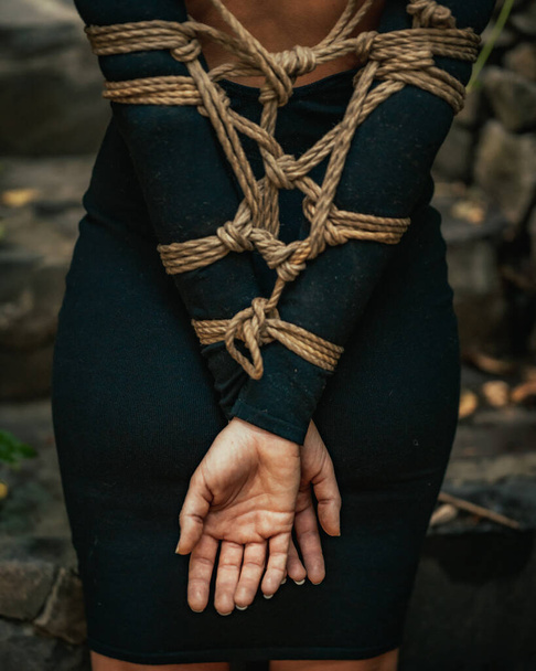 Een verticaal shot van de gebonden handen van een vrouw met een zwarte jurk in Guatemala - Foto, afbeelding