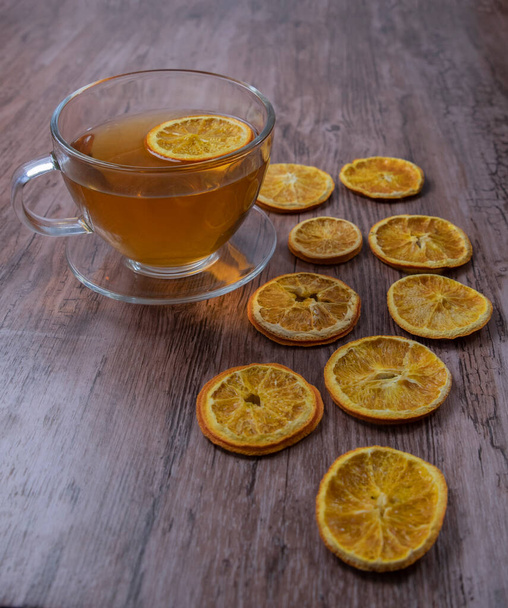 Šálek čaje s citrónovými plátky na dřevěném pozadí a suché pomerančové plátky - Fotografie, Obrázek