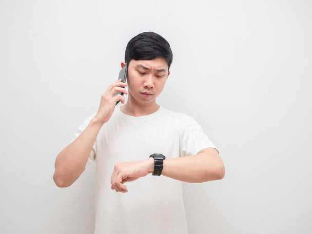 Man talking with cellphone and looking at his watch serious face on white background - Foto, Bild
