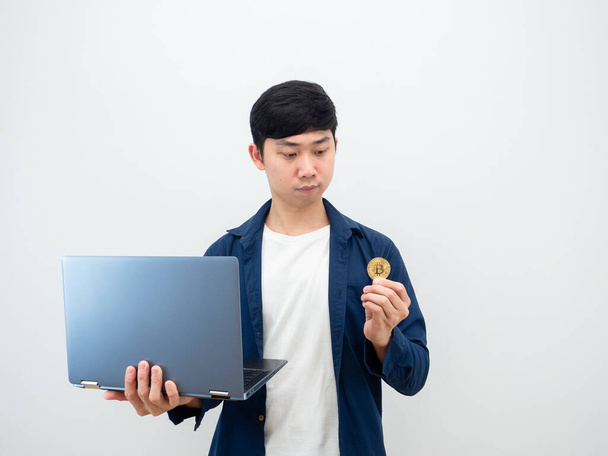 Asian man holding laptop and looking at bitcoin in hand on white background digital money concept - Fotó, kép