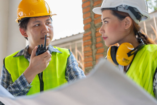 Asijský inženýr nebo mladá žena architekt nasadit přilbu pro bezpečnost a mluvit s dodavatelem na stavební tovární projekt, Koncepce týmové práce, Leadership koncept. - Fotografie, Obrázek