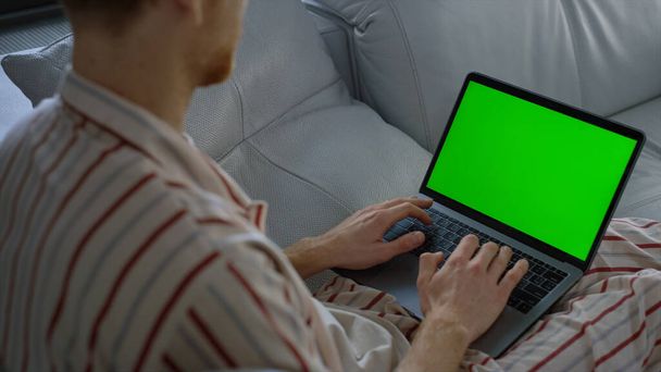 Freelancer browsing web green laptop screen close seup. Мужчина делает покупки онлайн выходные. Неизвестный успешный менеджер компании, работающий в домашнем офисе карантина. Финансовый консультант, проверяющий данные макета акций - Фото, изображение
