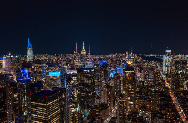 Αεροφωτογραφία της Μητρόπολης τη νύχτα. Πολύχρωμα φώτα νέον σε πολυώροφα κτίρια στην αστική περιοχή. Μανχάταν, Νέα Υόρκη, ΗΠΑ. - Φωτογραφία, εικόνα