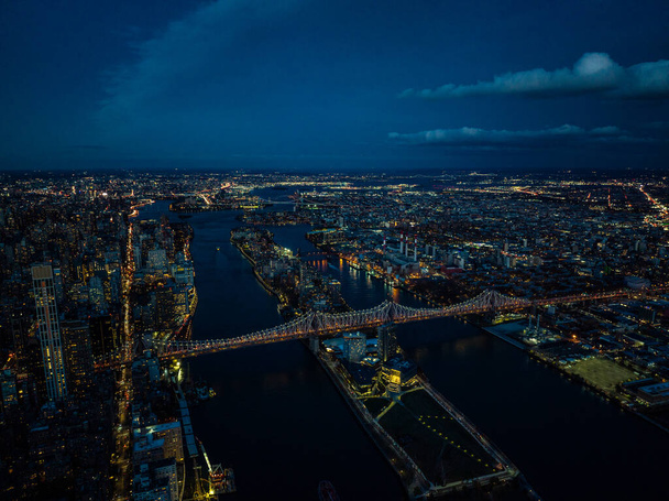 Αεροφωτογραφία της γέφυρας Κουίνσμπορο και του νησιού Ρούσβελτ μετά το ηλιοβασίλεμα. Βραδινή πανοραμική λήψη των φώτων της πόλης σε αστικές περιοχές. Νέα Υόρκη, ΗΠΑ. - Φωτογραφία, εικόνα