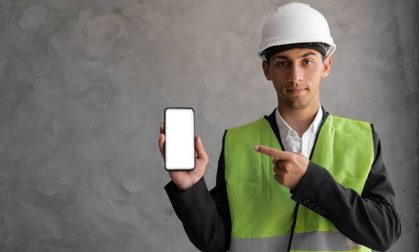 sonriente ingeniero árabe masculino o constructor en casco blanco y en general mostrando teléfono inteligente con pantalla vacía sobre fondo gris. profesión, construcción y concepto de construcción - Foto, Imagen